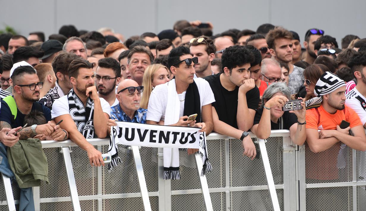 Para suporter bersiap menyambut kedatangan bintang baru Juventus, Cristiano Ronaldo, saat akan menjalani tes kesehatan di area Stadion Allianz, Turin, Senin (17/7/2018). CR 7 hijrah dari Real Madrid ke Juventus. (AFP/Miguel Medina)