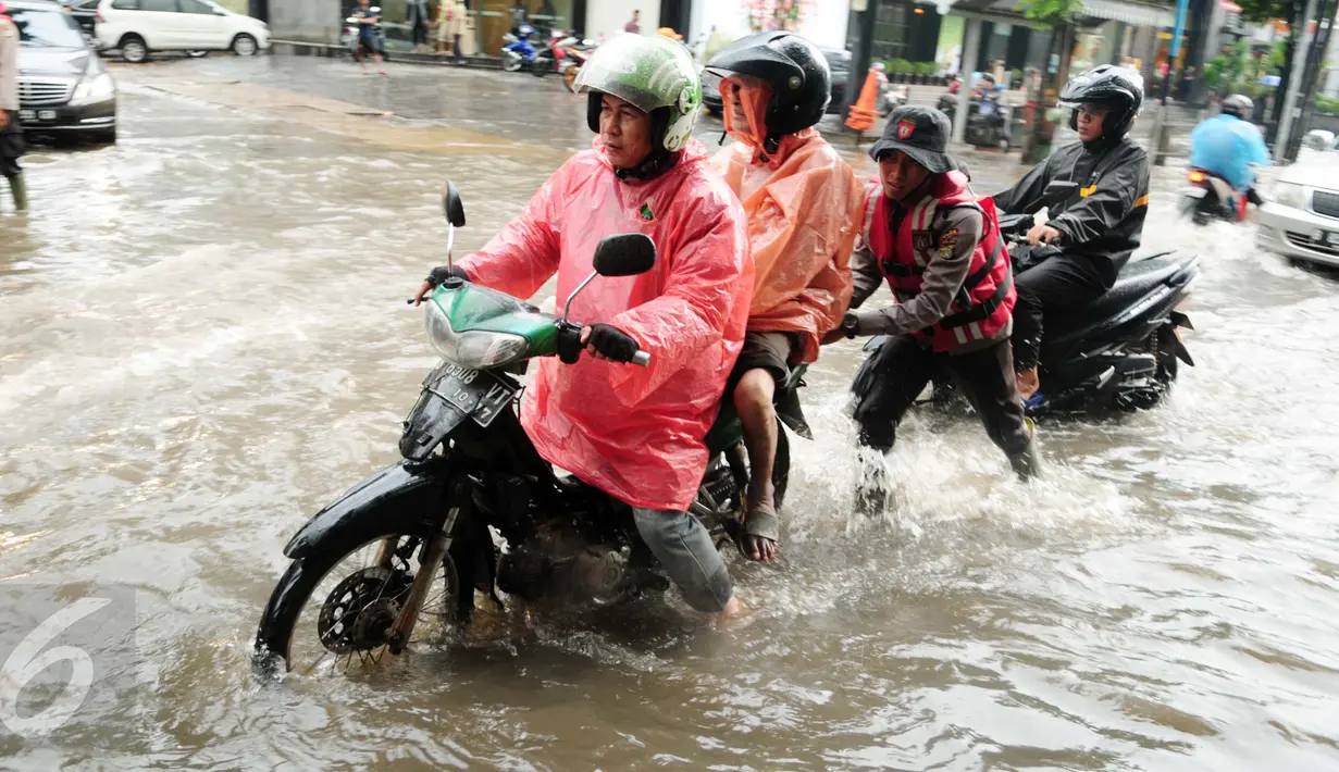 Seorang petugas membantu mendorong sepeda motor yang menerobos banjir di kawasan Kemang, Jakarta, Selasa (4/10). Hujan deras yang mengguyur Jakarta dan meluapnya kali Krukut menyebabkan wilayah Kemang kembali terendam banjir. (Liputan6.com/Gempur M Surya)