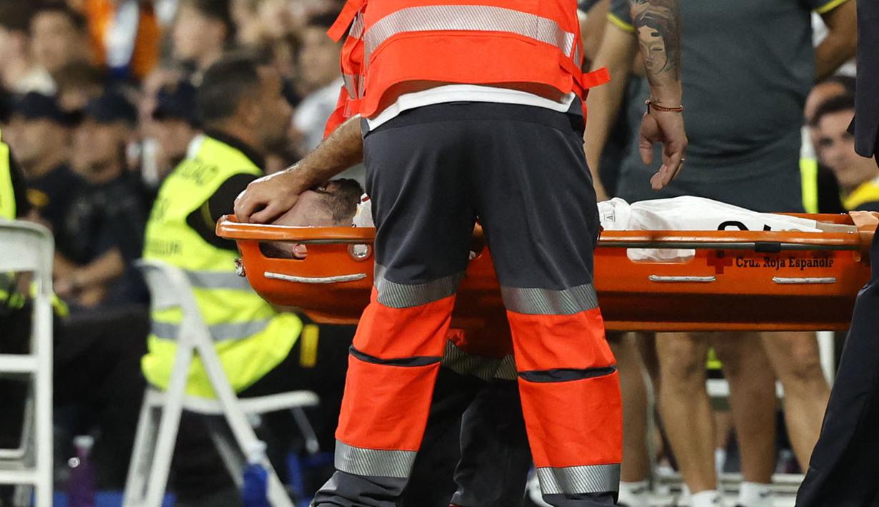 Ia pun kemudian mendapatkan pertolongan medis sembari ditandu ke luar lapangan pertandingan. Carvajal dipastikan mengalami cedera lutut ligamen ACL yang serius. (AFP/Oscar Del Pozo)