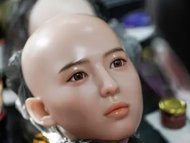 Seorang pekerja melukis wajah boneka seks di sebuah pabrik yang terletak di Dalian, China, Kamis (1/2). Pabrik boneka seks ini ingin menghubungkan orang-orang yang kesepian dan pensiunan dengan jenis pendamping baru. (AFP PHOTO/FRED DUFOUR)