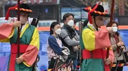 Pengunjung yang mengenakan masker menyaksikan upacara pergantian penjaga istana di gerbang utama Istana Deoksugung di Seoul, Rabu (18/11/2020). Upacara Pergantian Penjaga Kerajaan diadakan mulai hari Selasa hingga Minggu, sebanyak tiga kali sehari (11:00, 14:00, 15:30). (Jung Yeon-je AFP)