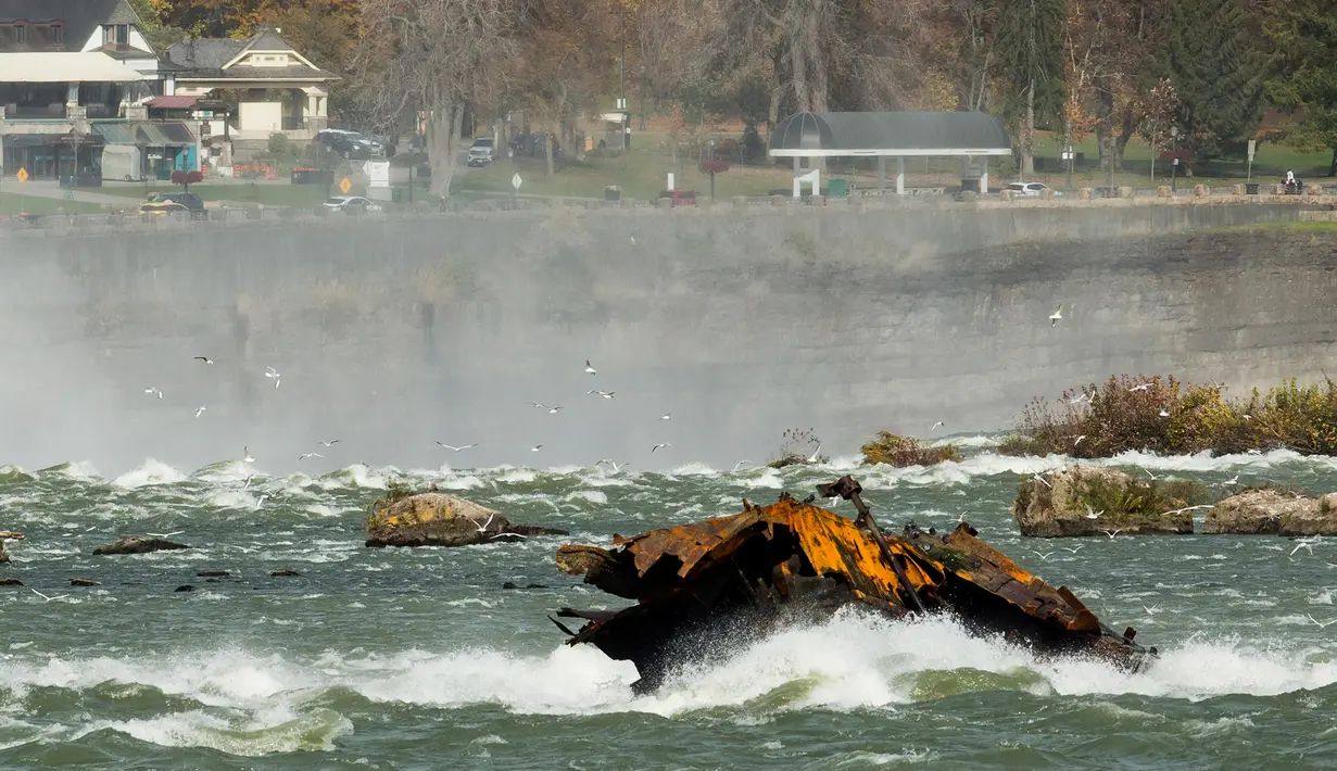 Sebuah kapal yang karam di atas Horseshoe Falls dari Air Terjun Niagara setelah bergeser di Ontario, Kanada, Senin (4/11/2019). Dikenal sebagai 'Iron Scow', kapal tersebut merupakan ikon Air Terjun Niagara setelah terjebak di batu selama 101 tahun. (Tara Walton/The Canadian Press via AP)