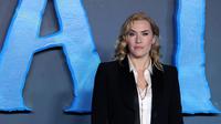 Kate Winslet berpose saat pemotretan untuk film 'Avatar: The Way of Water' di London, Minggu, 4 Desember 2022. Si cantik mengangkat tubuhnya dengan sepasang sepatu bot kulit. (AFP/Isabel Infantes)