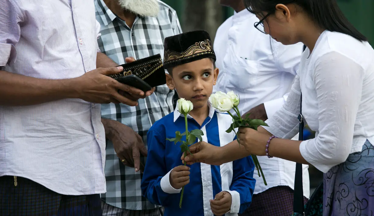 Umat Buddha Myanmar membagikan mawar putih kepada bocah Muslim setelah melaksanakan salat Id pada perayaaan Idul Fitri di kota Than Lyin, Yangon, Rabu (5/6/2019). Tindakan itu dilakukan beberapa minggu setelah kelompok garis keras berusaha menghapuskan doa selama bulan Ramadhan. (Sai Aung MAIN/AFP)