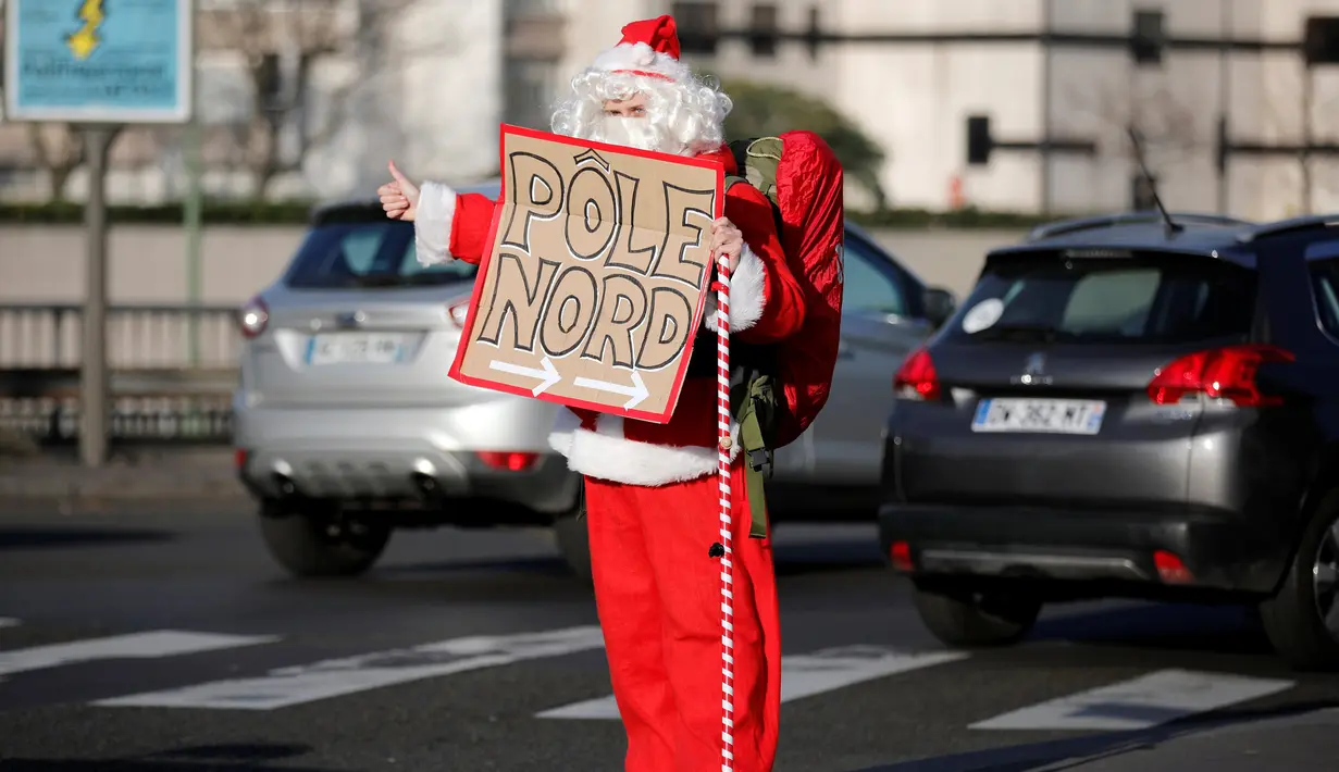 Remi Le Calvez mengenakan kostum Santa Claus, menunggu mobil yang bisa ditumpangi di Paris, Prancis, Selasa (6/12). Pada perjalannya kali ini, Remi mencari tumpangan yang akan membawanya ke Rovaniemi di Lapland, Finlandia Utara. (Reuters/Benoit Tessier)