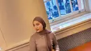 Ia mengenakan atasan lengan panjang coklat yang dipadukan dengan bawahan kain batik warna putih bermotif. Ia pun membawa shoulder bag coklat. [@camilliazr]