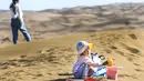 Seorang anak bermain pasir di kawasan wisata Gurun Kum Tag di Wilayah Shanshan, Kota Turpan, Daerah Otonom Uighur Xinjiang, China barat laut (22/9/2020). Gurun tersebut saat ini mencatat peningkatan arus wisatawan. (Xinhua/Wang Fei)