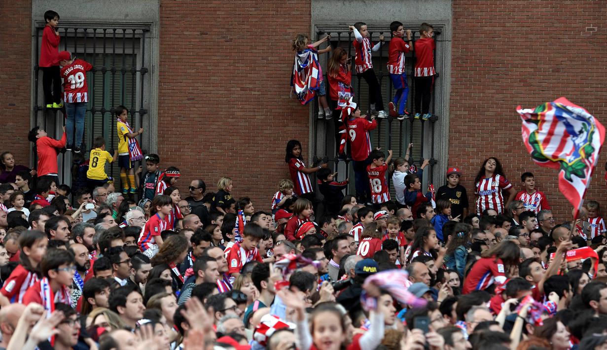 Warga Madrid tumpah ke jalan saat menyambut konvoi Atletico Madrid merayakan gelar Liga Europa di Madrid, Jumat (18/5/2018). Kota Madrid menjadi merah saat perayaan gelar juara Atletico. (AFP/Oscar Del Pozo)