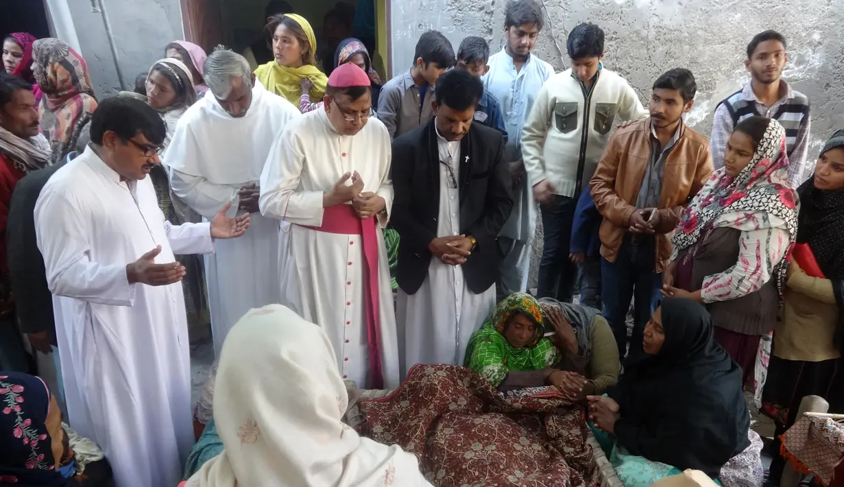 Pemuka agama berdoa di dekat jenazah korban minuman keras oploson di Toba Tek Singh, sekitar 338 km dari Islamabad, Selasa (27/12). Selain memakan korban jiwa, minuman oplosan rumahan itu juga membuat puluhan orang dilarikan ke rumah sakit. (STR/AFP)