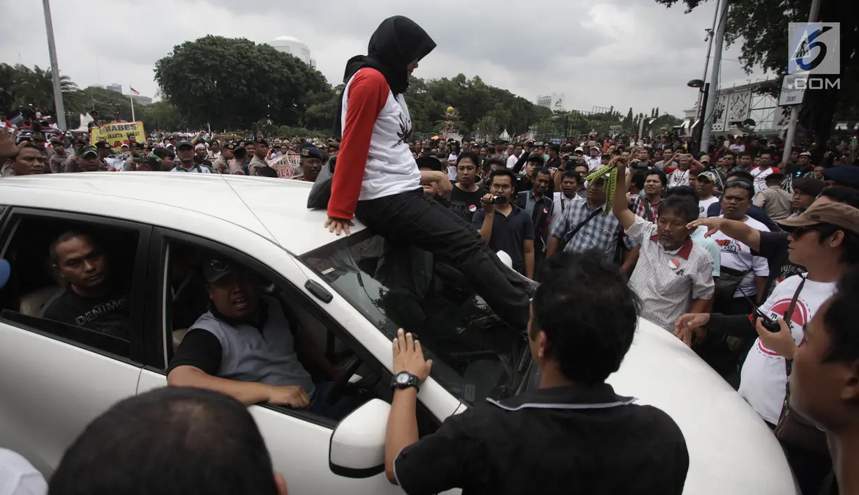 Demonstran berusaha mencegat driver online yang masih beroperasi saat unjuk rasa di depan Istana Negara, Jakarta, Rabu (14/2). Aksi pemberhentian mobil taksi online itu membuat situasi tegang antar pengemudi dan demonstran. (Liputan6.com/Arya Manggala)