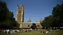 Orang-orang berbincang saat bersantai di bawah sinar matahari di Victoria Tower Gardens dekat Gedung Parlemen di London (23/7/2019). Suhu melonjak di atas 30C (86F) di Inggris pada 23 Juli dengan para peramal cuaca memperkirakan suhu setinggi 37C (96.8F) sebelum akhir pekan. (AFP Photo/Ben Stansall)