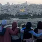 Warga Palestina berkumpul untuk berbuka puasa selama bulan suci Ramadan dengan latar belakang Kota Tua Yerusalem dan kompleks Masjid al-Aqsa yang ditutup selama krisis pandemi coronavirus yang baru di Bukit Zaitun (19/5/2020). (AFP/Ahmad Gharabli)