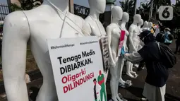 Aktivis Greenpeace Indonesia memasang poster pada puluhan maneken saat menggelar aksi damai di depan gerbang kompleks DPR, Jakarta Pusat, Senin (29/6/2020). Aksi tersebut dilakukan sebagai bentuk penolakan terhadap RUU Omnibus Law. (Liputan6.com/Johan Tallo)