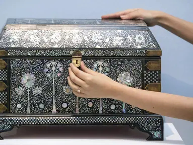 Karyawan rumah lelang Sotheby melihat peti mati bertatahkan mutiara yang diperkirakan bernilai 250.000-350.000 pound sterling sebagai bagian dari penjualan Arts of the Islamic World dan India pada 31 Maret di London, Inggris, Senin (29/3/2021). (Dominic Lipinski/PA via AP)