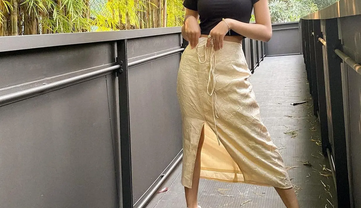 Hobi pakai outfit yang simple, Naura Ayu kali ini memadukan t-shirt hitam dan rok belah pinggir berwarna beige. Menyesuaikan look yang sesuai dengan usianya, Naura Ayu mengenakan sneaker putih.