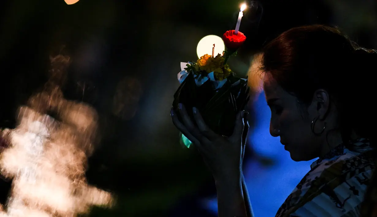 Seorang wanita berdoa sebelum menghayutkan 'krathong' untuk merayakan festival Loy Krathong di sebuah danau di Bangkok, Kamis (22/11). Loy Krathong dirayakan setiap tahun di seluruh Thailand sebagai penghormatan kepada dewi air. (Jewel SAMAD/AFP)