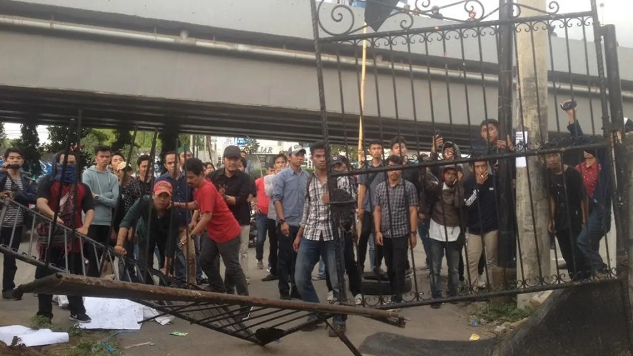 Massa HMI Unibos Makassar merusak pagar kantor Kejati Sulsel saat berunjuk rasa menagih keseriusan Kejati Sulsel menangkap buron kasus korupsi penyewaan lahan negara dan dugaan TPPU di Makassar, Jentang (Liputan6.com/ Eka Hakim)