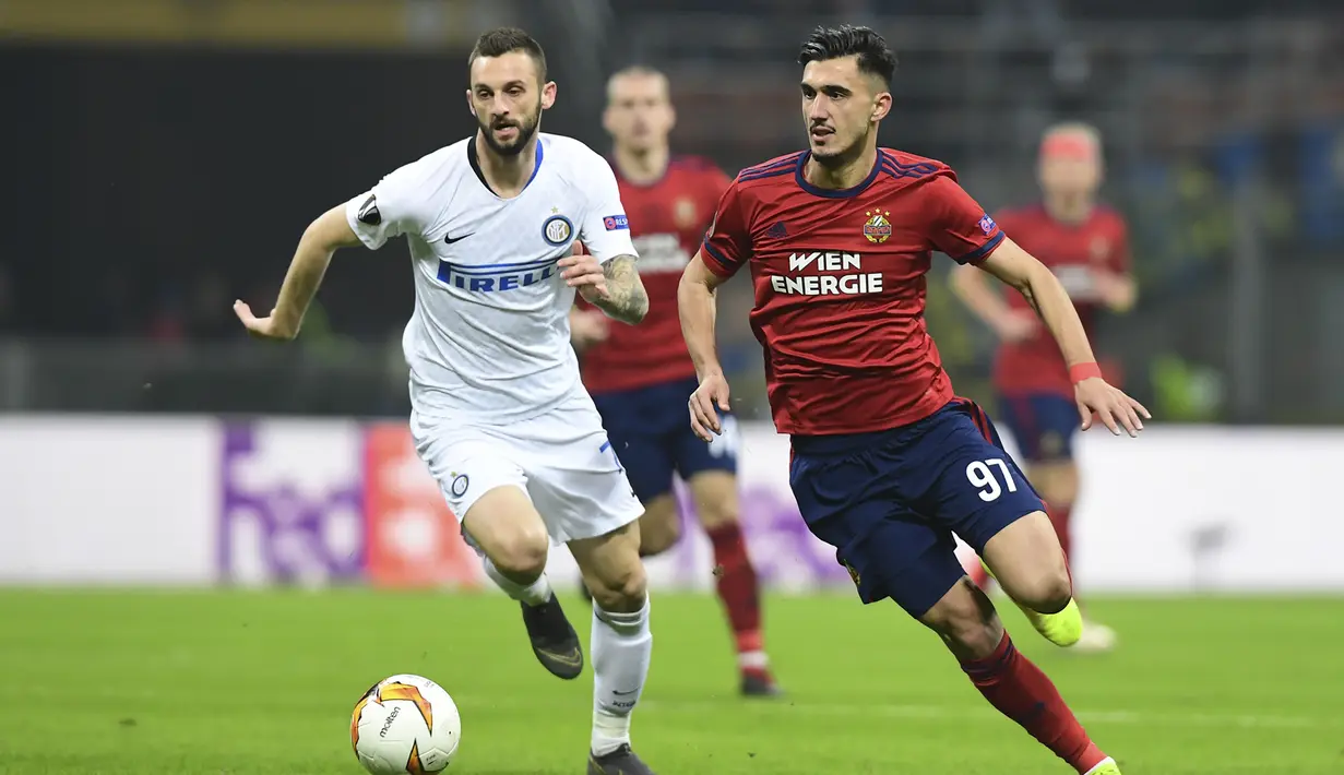 Gelandang Rapid Wien, Andrei Ivan melewati Marcelo Brozovic pada leg 2, babak 16 besar Liga Europa yang berlangsung di stadion Giuseppe Meazza, Milan, Jumat (22/2). Inter Milan menang 4-0 atas rapid Wien. (AFP/Miguel Medina)