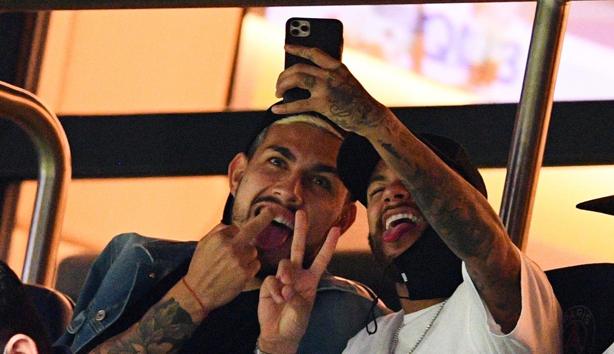 Pemain PSG, Neymar dan Leandro Paredes, melakukan swafoto saat menyaksikan pertandingan antara PSG melawan Metz pada laga Liga Prancis di Stadion Parc des Princes, Kamis (17/9/2020). Akibat pertikaian di laga melawan Marseille, Neymar dihukum larangan dua pertandingan. (AFP/Franck Fife)