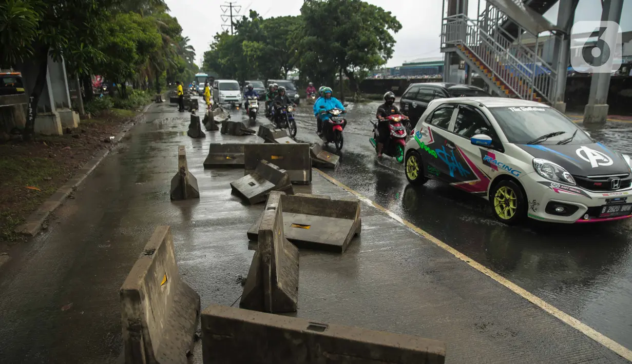 Kendaraan melintas dekat separator busway yang berserakan pascabanjir di Jalan Daan Mogot, Cengkareng, Jakarta, Jumat (3/1/2020). Separator busway tersebut berantakan akibat banjir yang menerjang sejak kemarin. (Liputan6.com/Faizal Fanani)