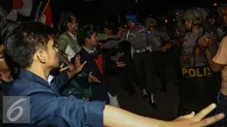 Massa aksi berhadapan dengan petugas polisi saat menggelar aksi unjuk rasa di depan Istana Negara, Kamis (12/1). Massa mahasiswa berkumpul di depan Istana di kawasan Jalan Merdeka Barat dengan membakar ban. (Liputan6.com/Faizal Fanani)