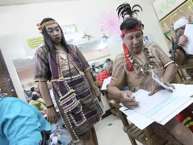 Kepala suku Igorot, Nicolas Cawed dibantu putrinya Mia Nicole mengisi kertas suara dalam pemilihan presiden di sebuah TPS di Baguio City, Manila Utara, Senin (9/5). Sekitar 50 juta warga Filipina mengikuti pemilihan Presiden. (AFP PHOTO/JJ LANDINGIN)