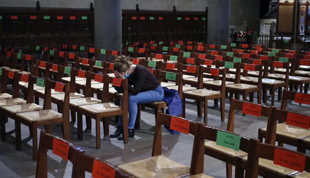 Seorang jemaah berdoa saat stiker jaga jarak sosial terpasang di kursi setelah kebaktian Kamis Putih di Gereja Saint Pierre de Montrouge, Paris, Prancis, Kamis (1/4/2021). Prancis bersiap melakukan lockdown setelah pemerintah menemukan adanya lonjakan kasus COVID-19. (AP Photo/Francois Mori)