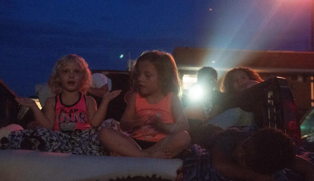 Orang-orang menonton film di luar ruangan saat pemutaran film drive-in di Family Drive-in, Virginia, 10 Agustus 2018. Drive-in merupakan bagian penting dalam industri hiburan di Amerika. (AFP PHOTO/Nicholas Kamm)