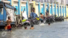 Sejumlah anak bermain genangan air banjir rob di kawasan akses pintu masuk menuju pelabuhan Kali Adem, Muara Angke, Jakarta, Senin (2/1). (Liputan6.com/Faizal Fanani)