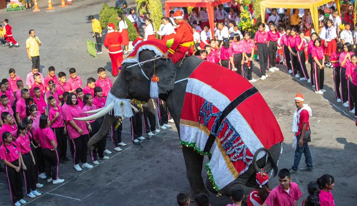 Gajah berkostum sinterklas tampil di depan siswa saat perayaan Natal di sekolah Jirasartwitthaya, Provinsi Ayutthaya, Thailand, Senin (23/12/2019). Acara tahunan ini digelar untuk menyambut Natal. (AP Photo/Sakchai Lalit)