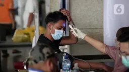 Seorang pria menjalani skrining saat mengikuti vaksinasi booster COVID-19 di Pasar Tanah Abang Blok A, Jakarta, Senin (4/4/2022). Vaksinasi yang diselenggarakan Polri ini diikuti warga sekitar dan pedagang Pasar Tanah Abang yang berencana mudik Lebaran. (Liputan6.com/Faizal Fanani)