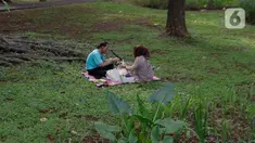 Warga membawa bekal makanan sambil menggelar tikar saat berwisata di Tebet Eco Park, Tebet, Jakarta, Senin (15/4/2024). (Liputan6.com/Herman Zakharia)