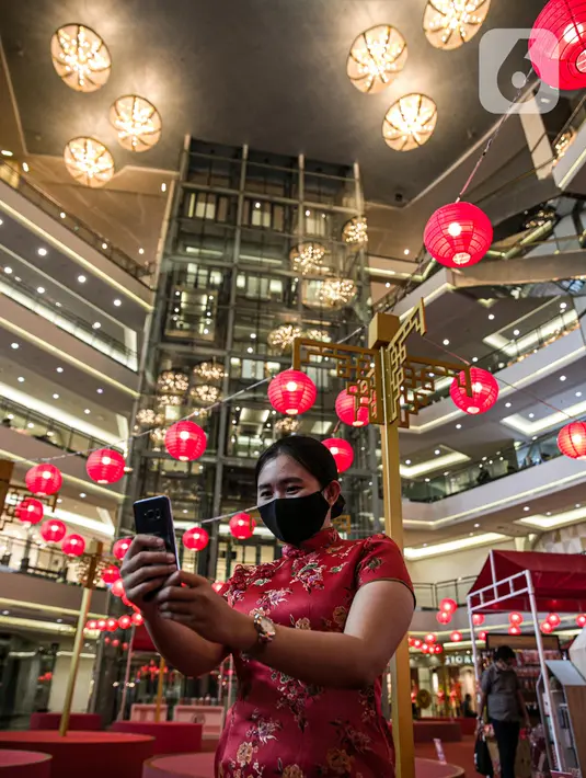 Seorang perempuan berswafoto dengan latar belakang ornamen dekorasi Imlek di Mall Taman Anggrek, Jakarta, Kamis (28/1/2021). Berbagai hiasan khas Tionghoa mulai mewarnai pusat perbelanjaan di ibu kota. (Liputan6.com/Faizal Fanani)
