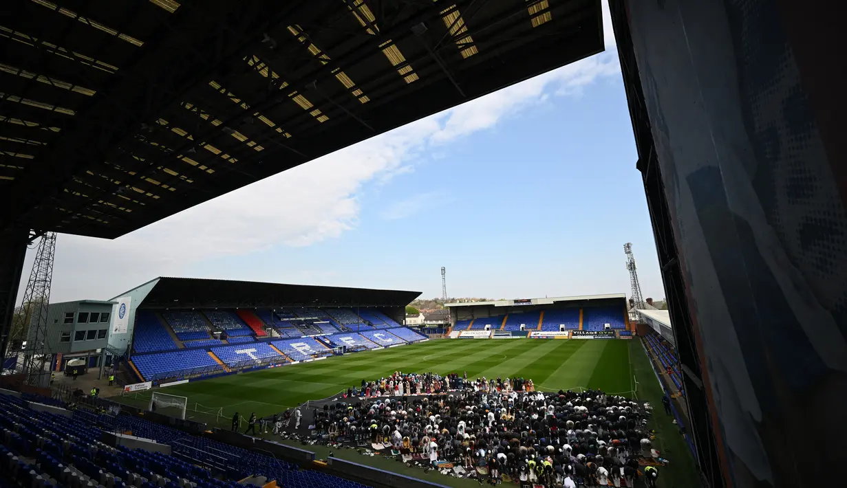 Umat Muslim berdoa pada hari pertama Idul Fitri, yang menandai akhir bulan puasa Ramadhan, di lapangan di stadion Prenton Park milik Tranmere Rovers di Birkenhead, barat laut Inggris, pada 21 April 2023. (AFP/Paul Ellis)