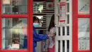 Seorang perempuan yang mengenakan masker membuka pintu toko optik di kota Quezon, Filipina, Selasa (22/9/2020). Presiden Filipina Rodrigo Duterte mengatakan telah memperpanjang status masa darurat virus corona (Covid-19) di negaranya hingga satu tahun ke depan. (AP Photo/Aaron Favila)