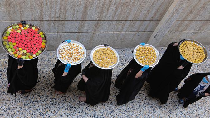 Sejumlah perempuan membawa kue untuk perayaan Idul Fitri yang akan datang di Basra, Irak, Jumat (22/5/2020). Idul Fitri menandai berakhirnya bulan suci Ramadan. (AP Photo/Nabil al-Jurani)