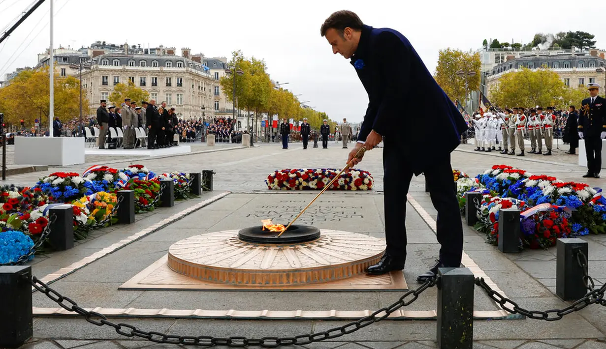 Presiden Prancis Emmanuel Macron mengatur nyala api di Makam Prajurit Tak Dikenal saat upacara di Arc de Triomphe, Paris, Prancis, 11 November 2022. Upacara ini digelar untuk menandai peringatan 104 tahun Gencatan Senjata 11 November 1918 yang mengakhiri Perang Dunia I. (Gonzalo Fuentes/Pool via AP)