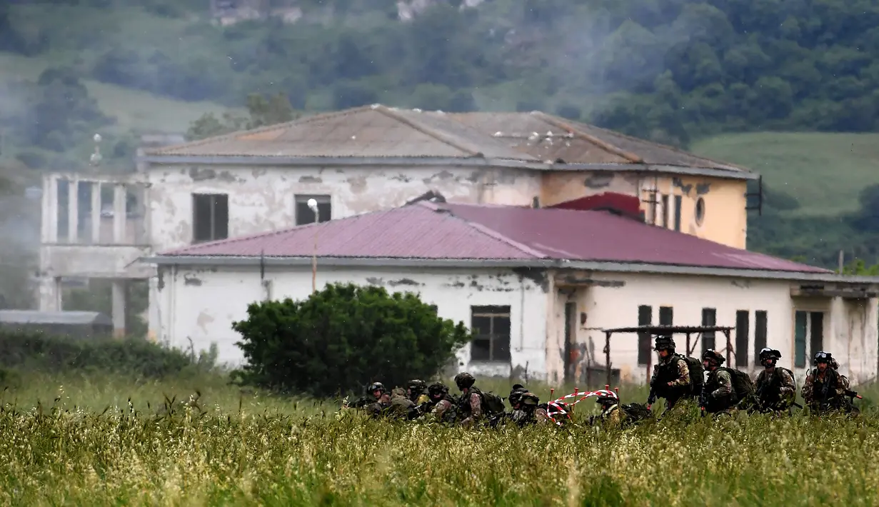 Sejumlah tentara Italia berjalan di rerumputan saat mengambil bagian dalam latihan militer di sebuah kamp pelatihan di Tarquinia, dekat Roma, (21/5).  (AFP Photo/Tiziana Fabi)