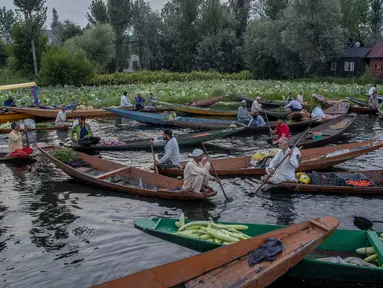 Laki-laki Kashmir menjual produk mereka di pasar sayur terapung di Danau Dal, Srinagar, Kashmir, India, Sabtu (7/8/2021). Sayuran yang diperdagangkan di pasar terapung ini dipasok ke Srinagar dan banyak kota di Lembah Kashmir. (AP Photo/Dar Yasin)