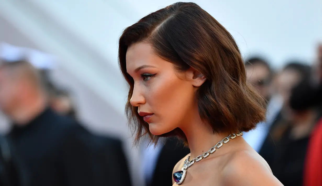 Model Bella Hadid berpose untuk fotografer di karpet merah pembukaan Festival Film Cannes 2017 di Prancis, Rabu (17/5). Penampilan Bella Hadid dilengkapi dengan kalung berbandul batu safir biru yang tampak mewah. (AFP PHOTO / Alberto PIZZOLI)