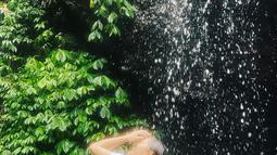 Tak hanya cukup memandangi keindahannya, Natalie Zenn menikmati aliran air terjun yang menghujaninya. Momen ini sukses jadi healing pemeran sinetron "Dewi Rindu" ini. (Liputan6.com/IG/@nataliezenn24).