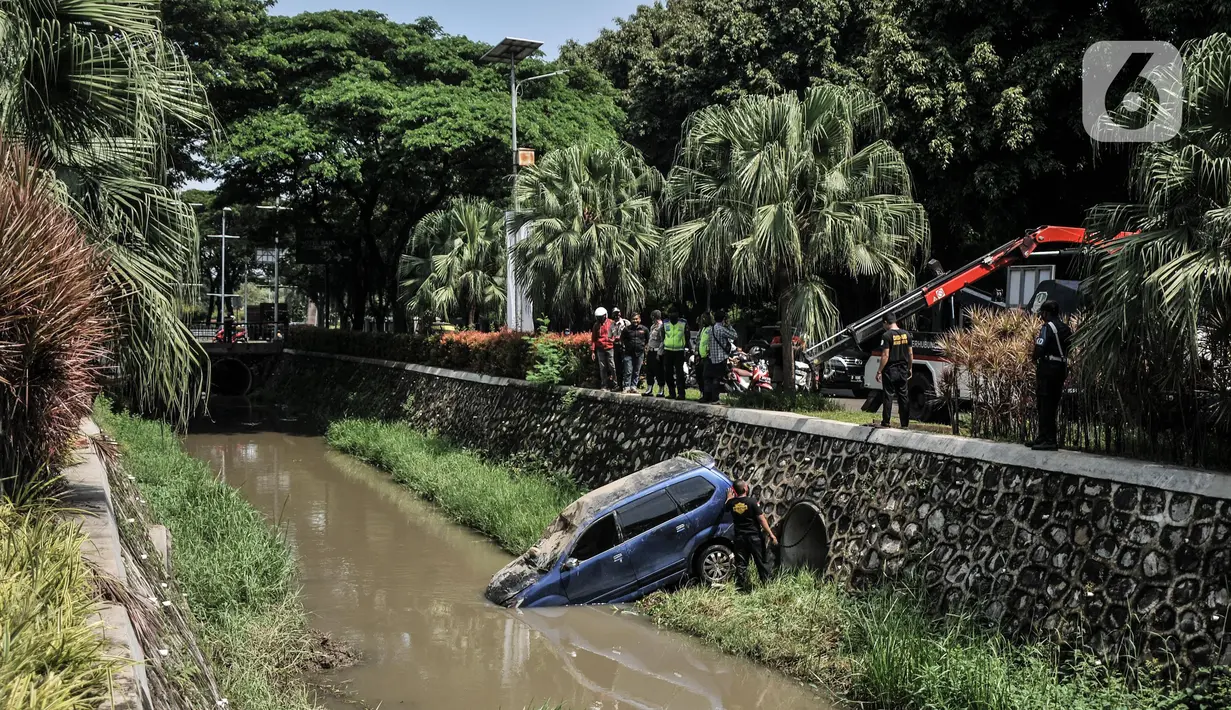 Petugas Dinas Perhubungan Kota Bekasi saat evakuasi mobil yang terperosok ke kali di Harapan Indah, Bekasi, Jawa Barat, Rabu (16/2/2022). Mobil jenis Avanza tersebut jatuh ke dalam kali usai mengalami kecelakaan tunggal akibat tergelincir saat melintasi tikungan. (merdeka.com/Iqbal S. Nugroho)