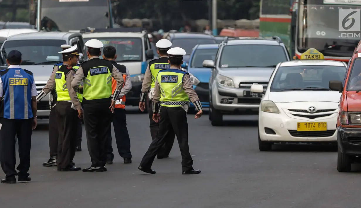 Petugas polisi mengatur lalu lintas saat pemberlakuan sistem ganjil genap di pintu masuk Gardu Tol Cibubur 2, Jakarta, Senin (16/4). Aturan ganjil genap ini diujicobakan di Gerbang Tol pada Senin 16 April 2018. (Liputan6.com/Faizal Fanani)