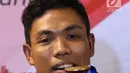 Pelari muda Indonesia, Lalu Muhammad Zohri menggigit medali emas saat upacara penyambutan di Terminal 3 Bandara Soetta, Tangerang, Selasa (17/7). Lalu M Zohri meraih emas lari 100m putra di Kejuaraan Dunia Atletik U-20. (Liputan6.com/Helmi Fithriansyah)