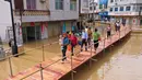 Jembatan yang membentang di atas genangan banjir memudahkan mobilitas warga dengan aman. (Foto: AFP)
