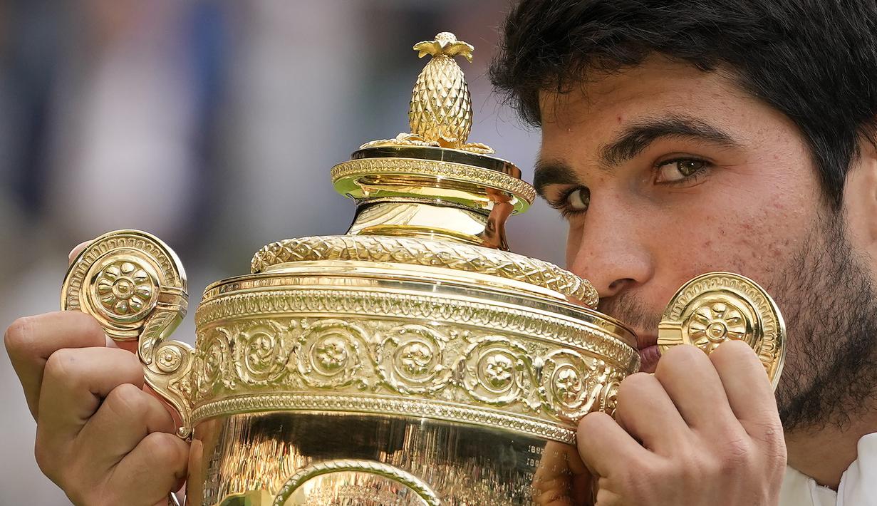 Selebrasi petenis Spanyol, Carlos Alcaraz dengan mencium trofi juara setelah memastikan kemenagan atas petenis Serbia, Novak Djokovic pada laga final tunggal putra turnamen tenis Grand Slam Wimbledon 2023 di All England Lawn and Tennis Club, London, Minggu (16/7/2023) malam WIB. Carlos Alcaraz menang 3-2 (1-6, 7-6 (6), 6-1, 3-6 dan 6-4). (AP Photo/Kirsty Wigglesworth)