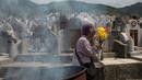 Seorang wanita membawa bunga selama festival Qingming di pemakaman di Hong Kong (5/4). Festival Qingming atau dikenal sebagai Hari Pembersihan Makam untuk menghormati orang yang dicintainya yang telah tiada. (AFP Photo/Isaac Lawrence)