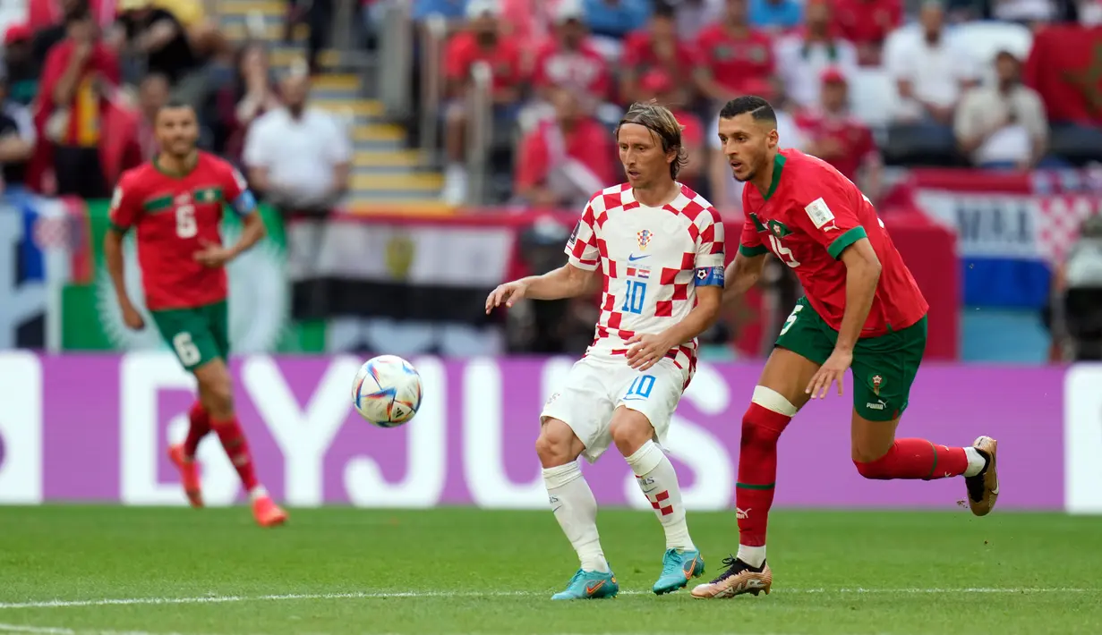 Pemain Kroasia Luka Modric (tengah) berebut bola dengan pemain Maroko Selim Amallah pada pertandingan sepak bola Grup F Piala Dunia 2022 di Stadion Al Bayt, Al Khor, Qatar, Rabu (23/11/2022). Pertandingan berakhir imbang dengan skor 0-0. (AP Photo/Aijaz Rahi)