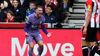 Gelandang Liverpool, Alexis Mac Allister, bersorak setelah mencetak gol ke gawang Bentford dan menyambut Mohamed Salah yang memberinya assist dalam pertandingan pekan ke-25 Liga Inggris 2023/2024, Sabtu (17/2/2024) malam WIB. (Adrian DENNIS / AFP)