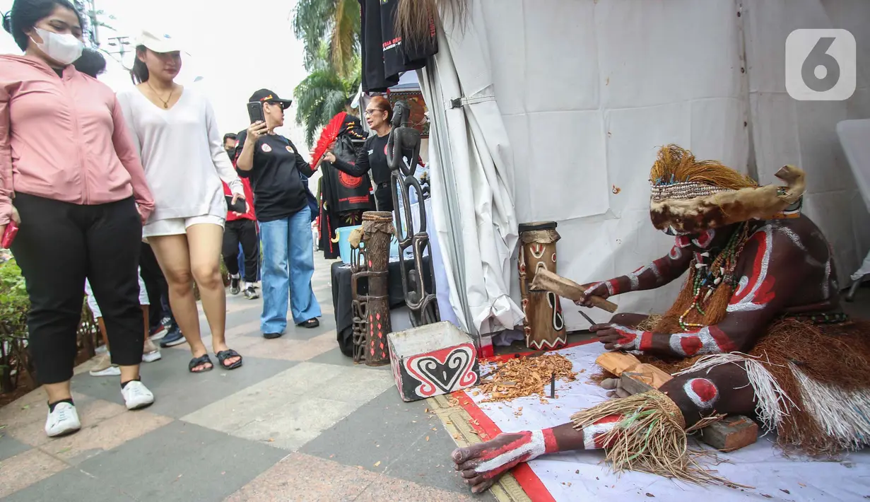 Warga melihat Suku dari Papua sedang mematung saat mengkampanyekan Sail Teluk Cenderawasih bertepatan dengan Hari Bebas Kendaraan Bermotor (HBKB), Kawasan Thamrin, Jakarta, Minggu (8/10/2023). (Liputan6.com/Angga Yuniar)